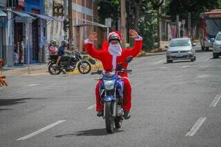 Bruno fantasiado de Papai Noel em cima da moto que usa para fazer entregas. (Foto: Marcos Maluf)
