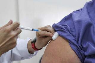 Profissional de saúde aplica dose da vacina contra covid em braço de homem (Foto: Henrique Kawaminami)