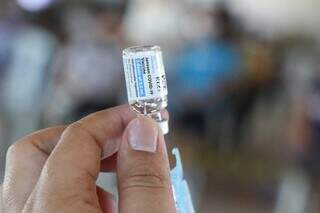 Mão segurando frasco com dose de vacina contra covid da Janssen. (Foto: Henrique Kawaminami)