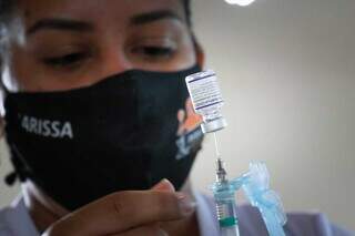 Profisisonal da saúde manuseando vacina em posto de imunização de Campo Grande. (Foto: Henrique Kawaminami)