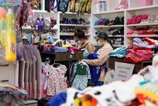 Clientes olhando roupas em loja de preço único no Jardim Antártica, região sul de Campo Grande (Foto: Henrique Kawaminami)