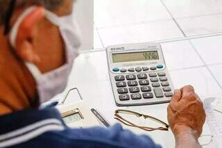 Homem faz cálculos para saber como pagará as contas no mês. (Foto: Henrique Kawaminami)