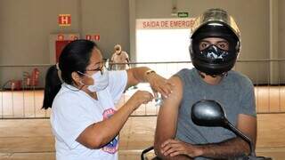 Profissional de saúde vacina motociclista em drive-thru da Capital (Foto: PMCG)