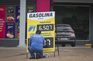 Funcionário de posto mudando valor da gasolina em placa. (Foto: Marcos Maluf)