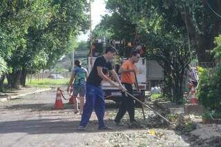 Moradores fazendo a limpeza da rua da praça. (Foto: Marcos Maluf)