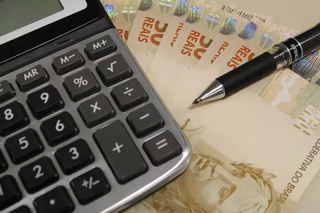 Dinheiro e calculadora utilizada para contabilizar dívidas (Foto: Marcos Santos/USP Imagens) 