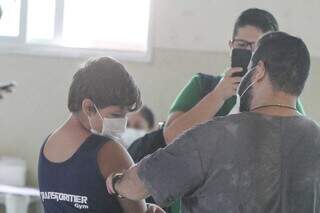 Menino recebe dose contra covid-19 em Campo Grande. (Foto: Marcos Maluf)