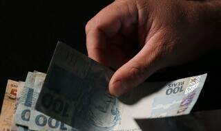 Beneficiário conta notas de dinheiro após saque em caixa eletrônico (Foto: José Cruz/Agência Brasil)