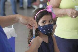 Criança olha para a injeção da vacina contra a covid-19, em vacinação feita na Escola Municipal Ana Lúcia de Oliveira Batista. (Foto: Marcos Maluf)