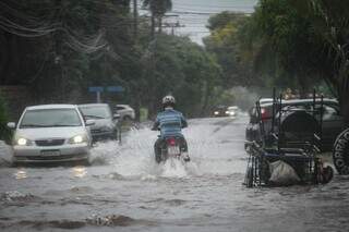 Veículos passando por ponto alagado no Bairro Tiradentes durante chuva em janeiro. (Foto: Marcos Maluf)