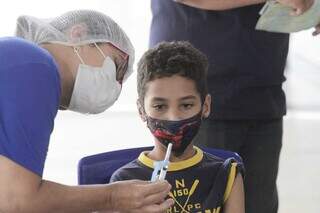 Profissional de saúde exibe vacina pediátrica a criança que foi vacinada no Estado. (Foto: Marcos Maluf)