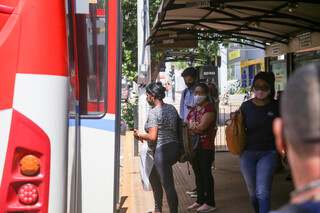 De máscara para reduzir chance de infecção viral, moradores da Capital entram em transporte coletivo nas ruas do Centro. (Foto: Paulo Francis)