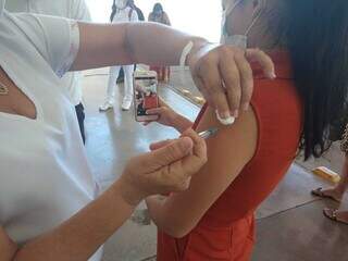 Mulher tira selfie enquanto é vacinada contra covid-19 em Campo Grande. (Foto: Cleber Gellio)
