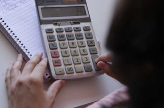 Mulher usa calculadora para contabilizar despesas. (Foto: Arquivo/Kísie Ainoã)