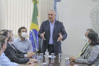 Governador Reinaldo Azambuja (PSDB) de pé, falando, no gabinete da governadoria. (Foto: Marcos Maluf)