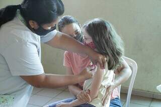 Mãe acompanha filha no momento de vacinação, em Campo Grande. (Foto: Kísie Ainoã)