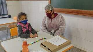 Profissional e criança em sala de aula de escola municipal. (Foto: Divulgação | PMCG)