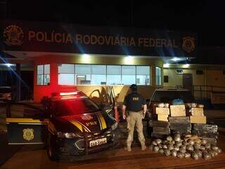 Policial rodoviário federal ao lado da carga de droga apreendida. (Foto: PRF) 