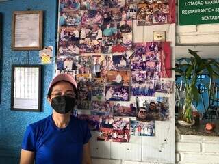 Suzana ao lado do mural com imagens dos clientes do restaurante. (Foto: Jéssica Fernandes)
