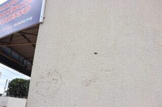 Marca de um disparo na parede de um estabelecimento em frente ao local do crime. (Foto: Paulo Francis)