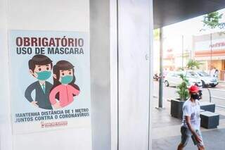 Cartaz exibe obrigação do uso de máscara em loja no Centro da Capital. (Foto: Henrique Kawaminami)