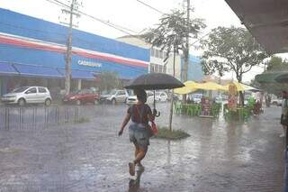 Mulher usa guarda-chuva para se proteger no Centro da Capital. (Foto: Paulo Francis)