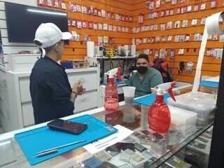 Em loja de manutenção de celulares uso de máscara está dividido. (Foto: Cleber Gellio)