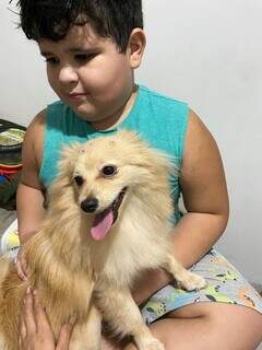 Criança que sofre com TEA pegando o cachorro no colo pela primeira vez após sessões para interação. (Foto: Jéssica Ferreira)