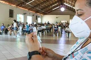 Profissional de saúde colocando na seringa uma dose de vacina. (Foto: Arquivo / Campo Grande News)