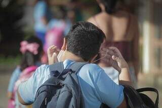 Aluno coloca máscara no rosto antes de entrar no colégio, nesta manhã, em Campo Grande. (Foto: Marcos Maluf)