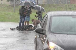 Com guarda-chuvas, testemunhas amparam vítima de acidente até a chegada do socorro (Foto: Marcos Maluf)