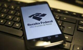 Aplicativo da Receita Federal em smartphone sobre teclado de computador (Foto: Agência Brasil/Marcello Casal Júnior)