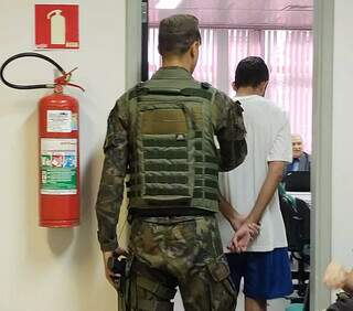 Momento em que militar entra em sala de audiência para acompanhar audiências (Foto: Mirian Machado)