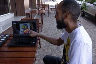 Anderson aponta para uma arte que integra a coleção de NFT&#39;s da Calango Doido. (Foto: Fabiano Foscacha)