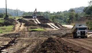 Pavimentação da Estrada do 21 segue em ritmo acelerado, apesar das chuvas, incluindo construção de pontes e bueiros.