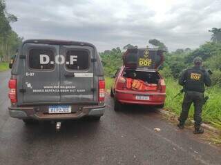 Policial do DOF ao lado do veículo em que o suspeito transportava a droga. (Foto: DOF) 