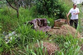 Aposentado recolhendo materiais em terreno baldio em frente a sua residência. (Foto: Henrique Kawaminami)