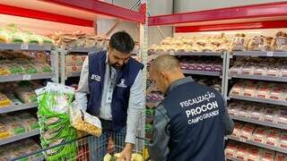 Fiscais descartando os produtos irregulares encontrados no supermercado. (Foto: Divulgação)
