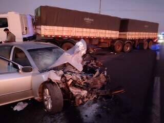 Carro destruído e caminhão ao fundo após acidente em rodovia. (Foto: News Informa)