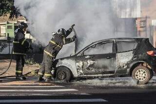 Carro destruído e bombeiros fazendo resfriamento. (Foto: Marcos Maluf)