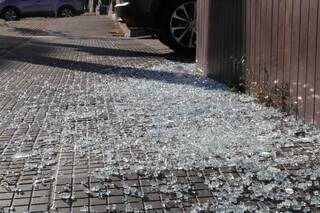 No chão, estilhaços da porta de vidro quebrada por tiro. (Foto: Kísie Ainoã)