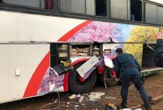 Policial observa tabletes de maconha em fundo falso na lateral de ônibus de turismo. (Foto: Divulgação)