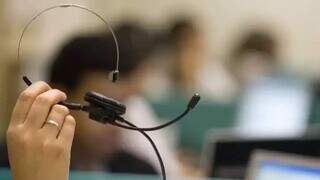 Trabalhador segurando fone usado para atendimento em call center. (Foto: Agência Brasil)