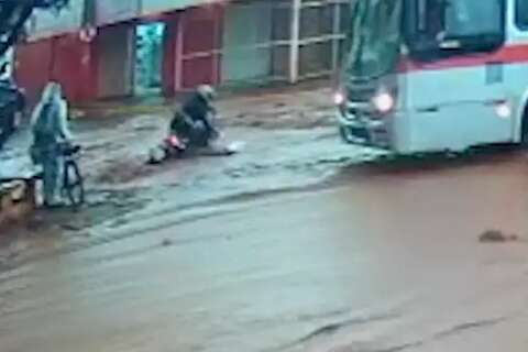 Mulher cai de moto em enxurrada ao ser pressionada por motorista de ônibus