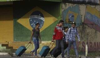 Com bagagem em mãos, imigrantes andam por calçada de Campo Grande. (Foto: Divulgação)