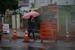 Jovem agasalhada e com guarda-chuva para se proteger da chuva. (Foto: Henrique Kawaminami) 