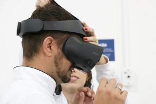 Virtual reality glasses are placed on the student.  (Photo: Henrique Kawaminami)