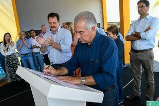 Governador durante assinatura e ao lado, prefeito de Chapadão do Sul, João Carlos Krug. (Foto: Divulgação)