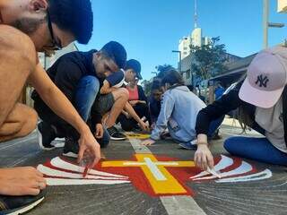 Fieis católicos se debruçando sobre as obras dos tapetes de Corpus Christi. (Foto: Carol Maldonado)