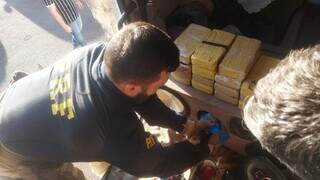 Tabletes de cocaína sendo retirados de compartimento secreto no caminhão. (Foto: Divulgação | PRF)